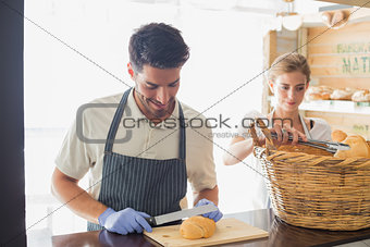 Young waiter with croissant at the coffee shop counter