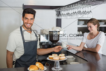 Friendly waiter giving coffee to a woman at coffee shop