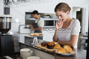 Thoughtful woman looking at sweet food at coffee shop