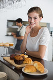 Confident cafe owner with sweet food at counter