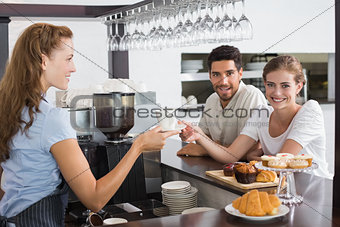 Female waiter giving coffee to a couple at coffee shop