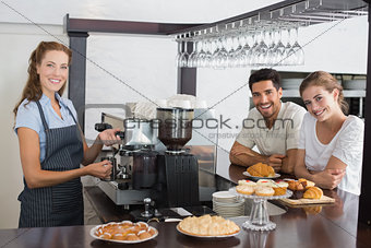 Smiling couple with female cafe owner at coffee shop