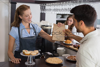 Cafe owner giving packed food to a couple at coffee shop