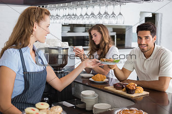 Cafe owner giving sandwich to a man at coffee shop