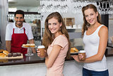 Male barista with women at counter in coffee shop