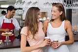 Cheerful friends with barista at counter in coffee shop