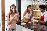 Woman drinking coffee with friend and male barista in coffee shop