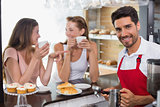 Women drinking coffee with barista at counter in coffee shop