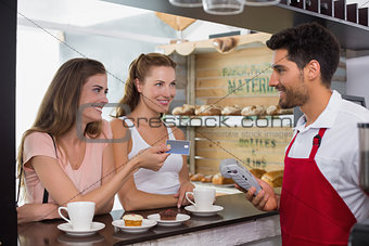 Friends with woman holding out credit card at coffee shop