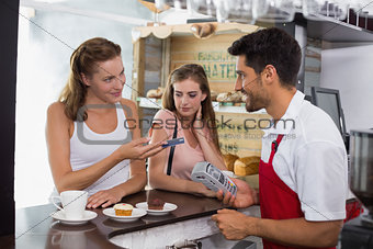 Friends paying bill at coffee shop using card bill