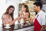 Barista giving pastry to woman at counter in coffee shop