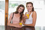 Female friends drinking orange juice at café