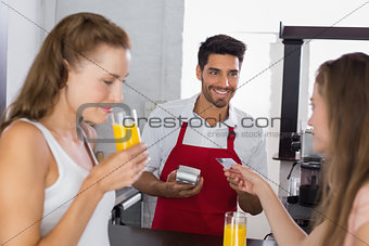 Women paying bill while drinking orange juice at coffee shop
