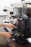 Mid section of a barista prepares espresso in coffee shop