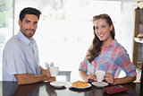 Smiling couple with coffee and croissant at coffee shop