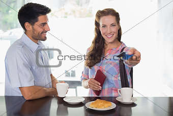 Couple with woman holding out credit card at coffee shop