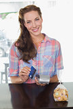 Smiling woman holding credit card at coffee shop counter