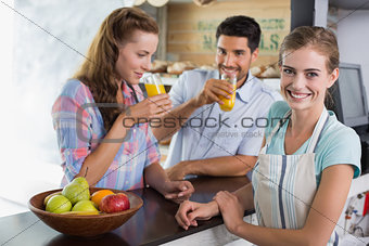 Waitress with couple drinking orange juice at coffee shop
