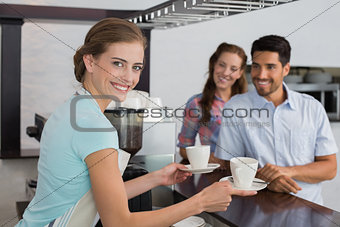 Smiling waitress giving coffee to a couple at coffee shop