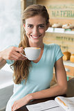 Smiling woman with coffee cup reading magazine in coffee shop