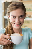 Smiling woman drinking coffee in coffee shop