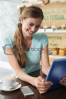 Woman with coffee cup using digital tablet in coffee shop