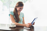 Smiling woman with coffee cup using digital tablet in coffee shop