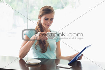 Woman with coffee cup using digital tablet in coffee shop