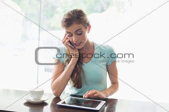 Woman with coffee cup using digital tablet and cellphone in coffee shop