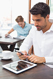 Concentrated man text messaging in coffee shop