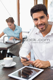 Smiling man text messaging in coffee shop