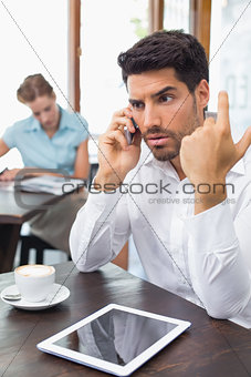 Serious man using mobile phone in coffee shop