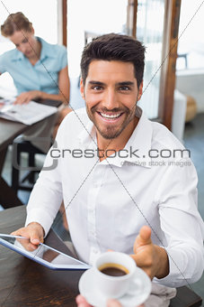 Man receiving coffee while using digital tablet in coffee shop