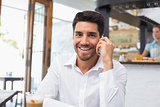 Smiling man using mobile phone in coffee shop
