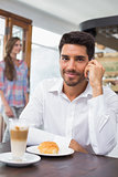 Smiling man using mobile phone in coffee shop