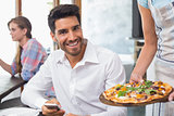 Waitress giving pizza to a smiling man at coffee shop