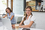 Smiling woman using laptop in coffee shop