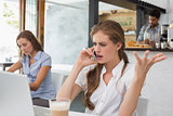 Annoyed woman using mobile phone in coffee shop