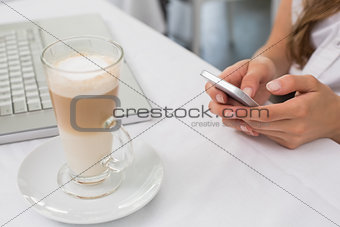 Close-up of drink with hands using mobile phone on table