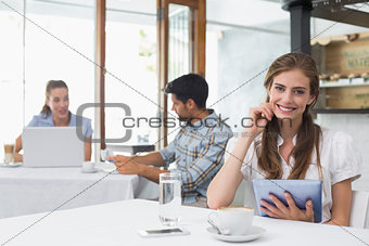 Smiling woman using digital tablet in coffee shop