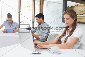 Concentrated woman using laptop in coffee shop