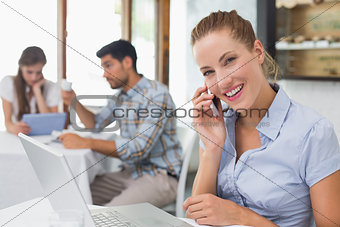 Woman using laptop and mobile phone in coffee shop