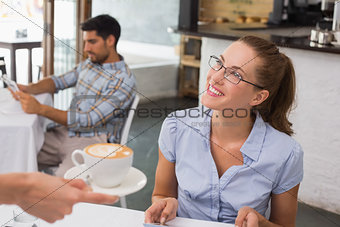 Smiling woman receiving coffee in coffee shop