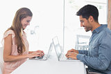 Side view of a happy couple using laptops