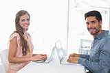 Happy young couple using laptops at table