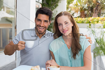 Smiling young couple with coffee cup at café