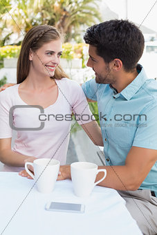 Smiling couple with coffee cups at café