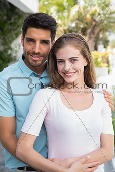 Loving man embracing woman from behind outdoors