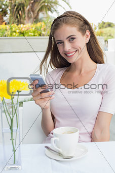 Woman with coffee cup text messaging in café