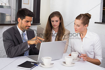Business people using laptop together at office desk